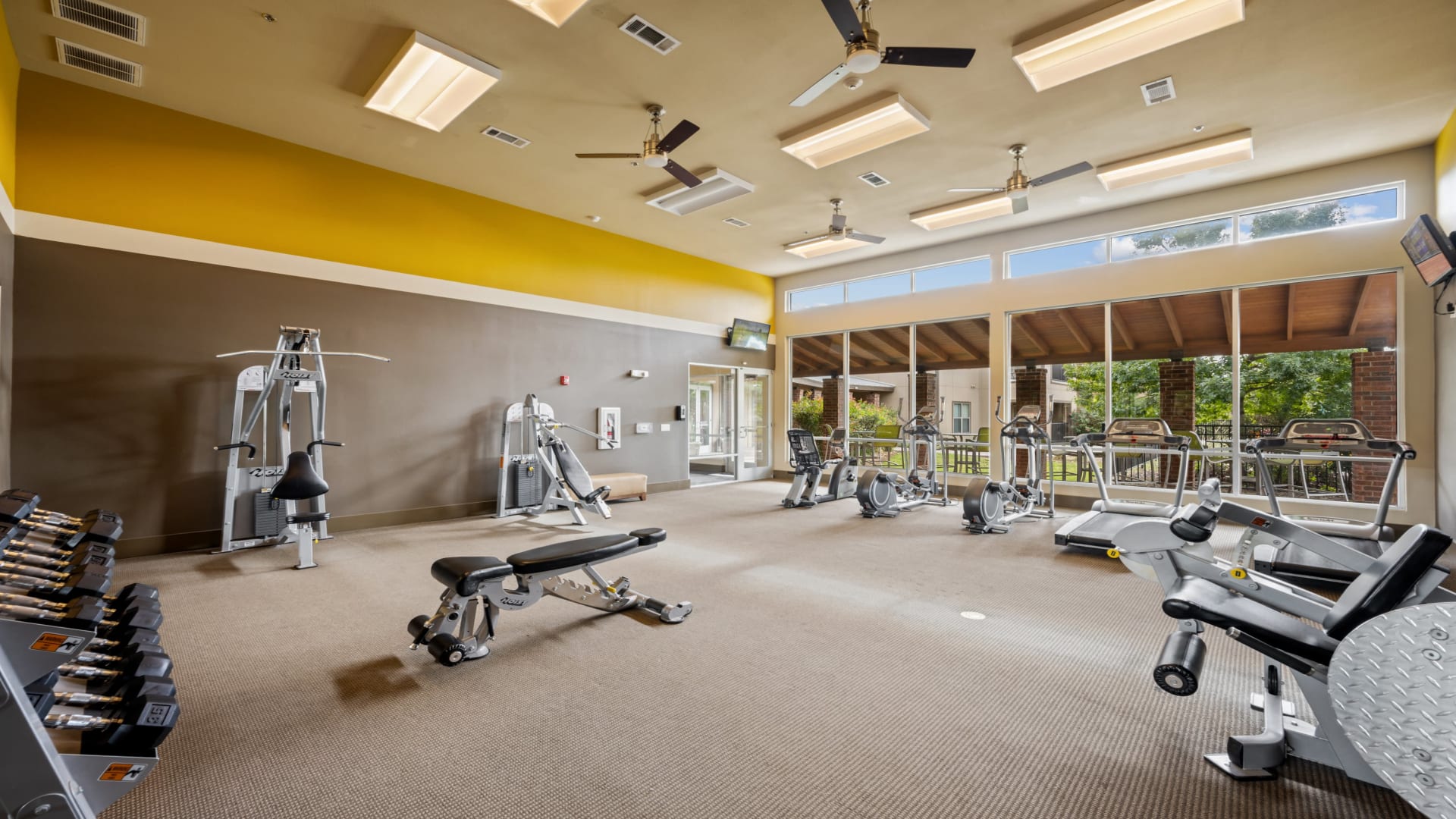 a gym room with a ceiling fan and yellow walls at The  BLVD