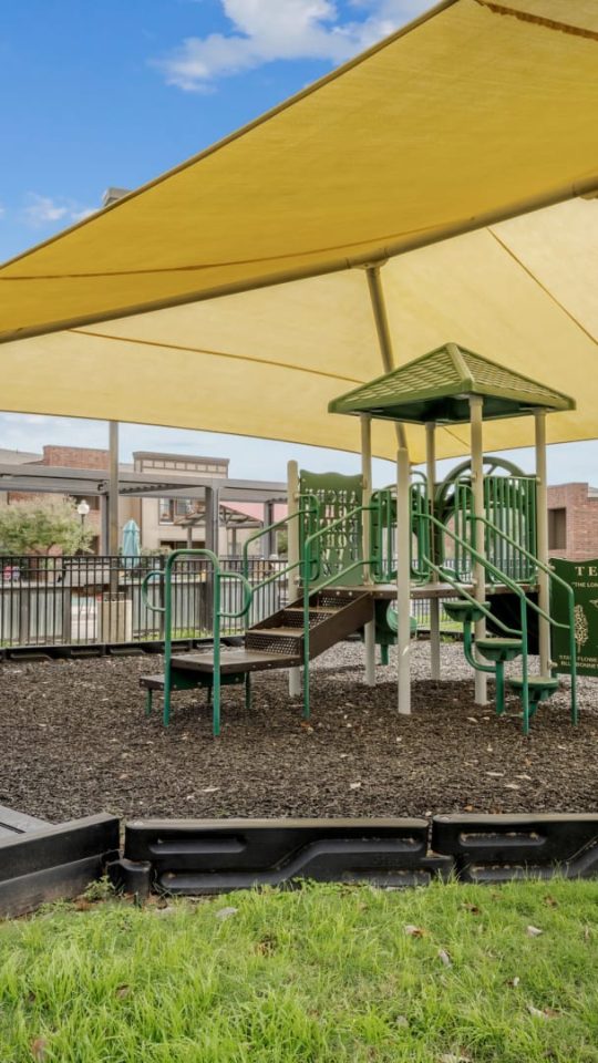 a playground area with a yellow canopy and a slide at The  BLVD