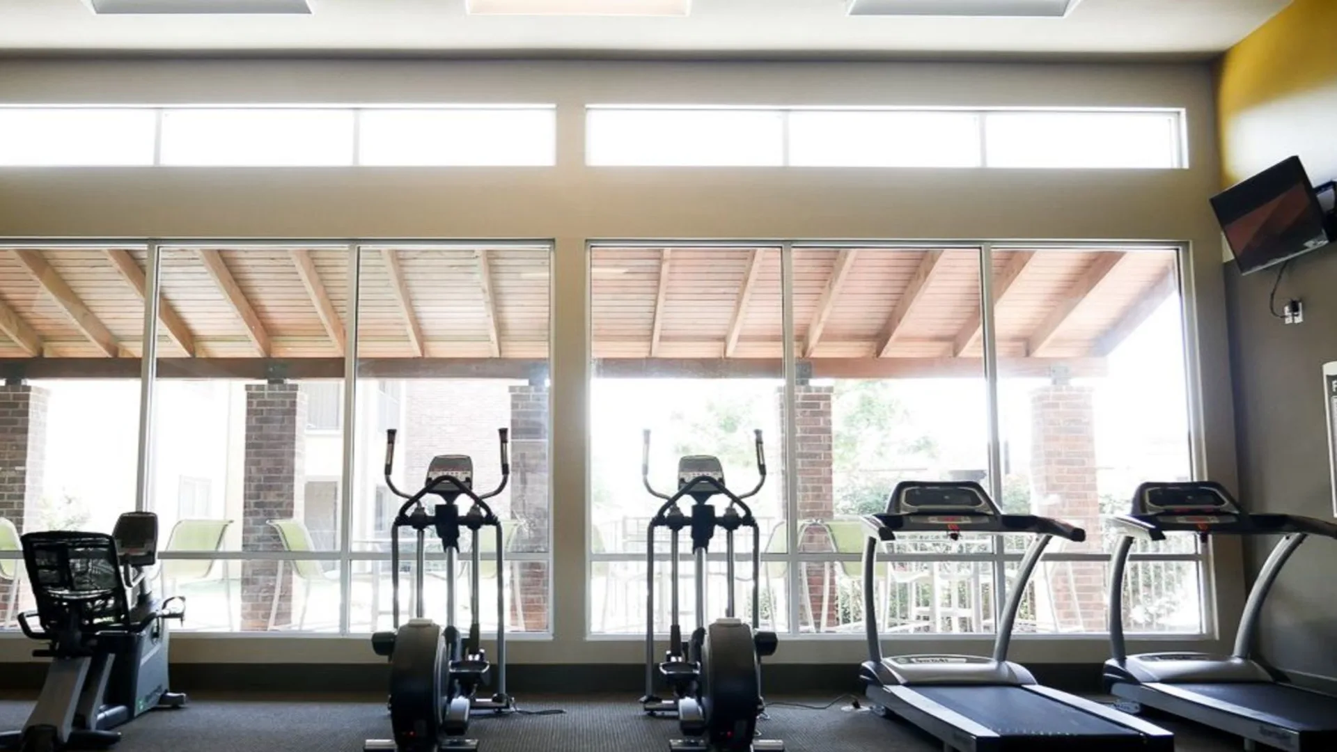 a gym room with tread machines and windows at The  BLVD